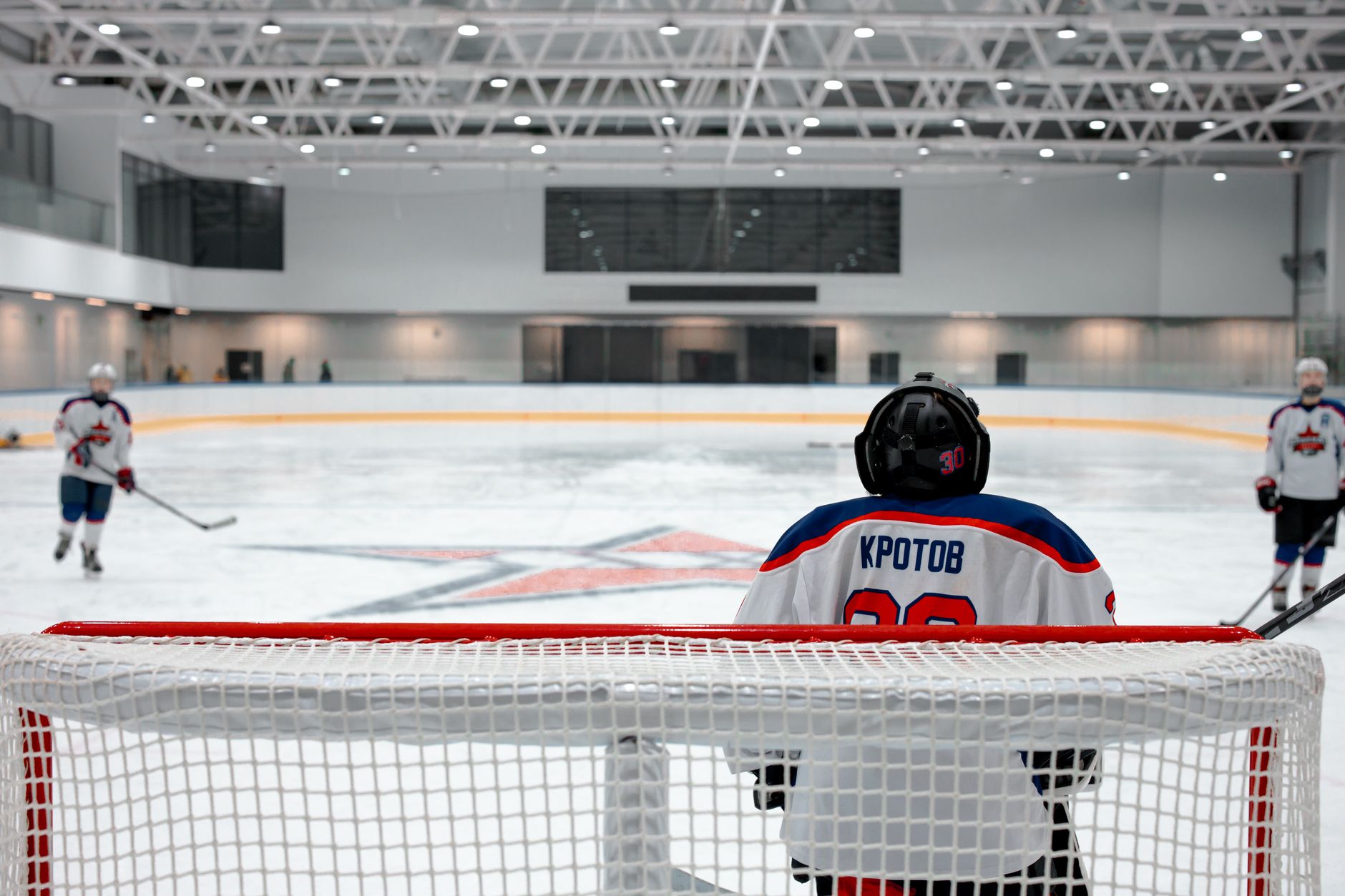 Ice hockey game with a focused goalie defending the goal, showcasing skill and teamwork indoors.