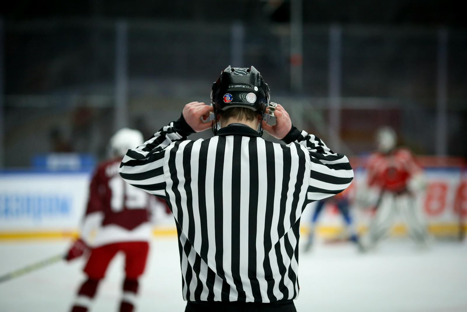 Ice hockey referee overseeing a game from the boards