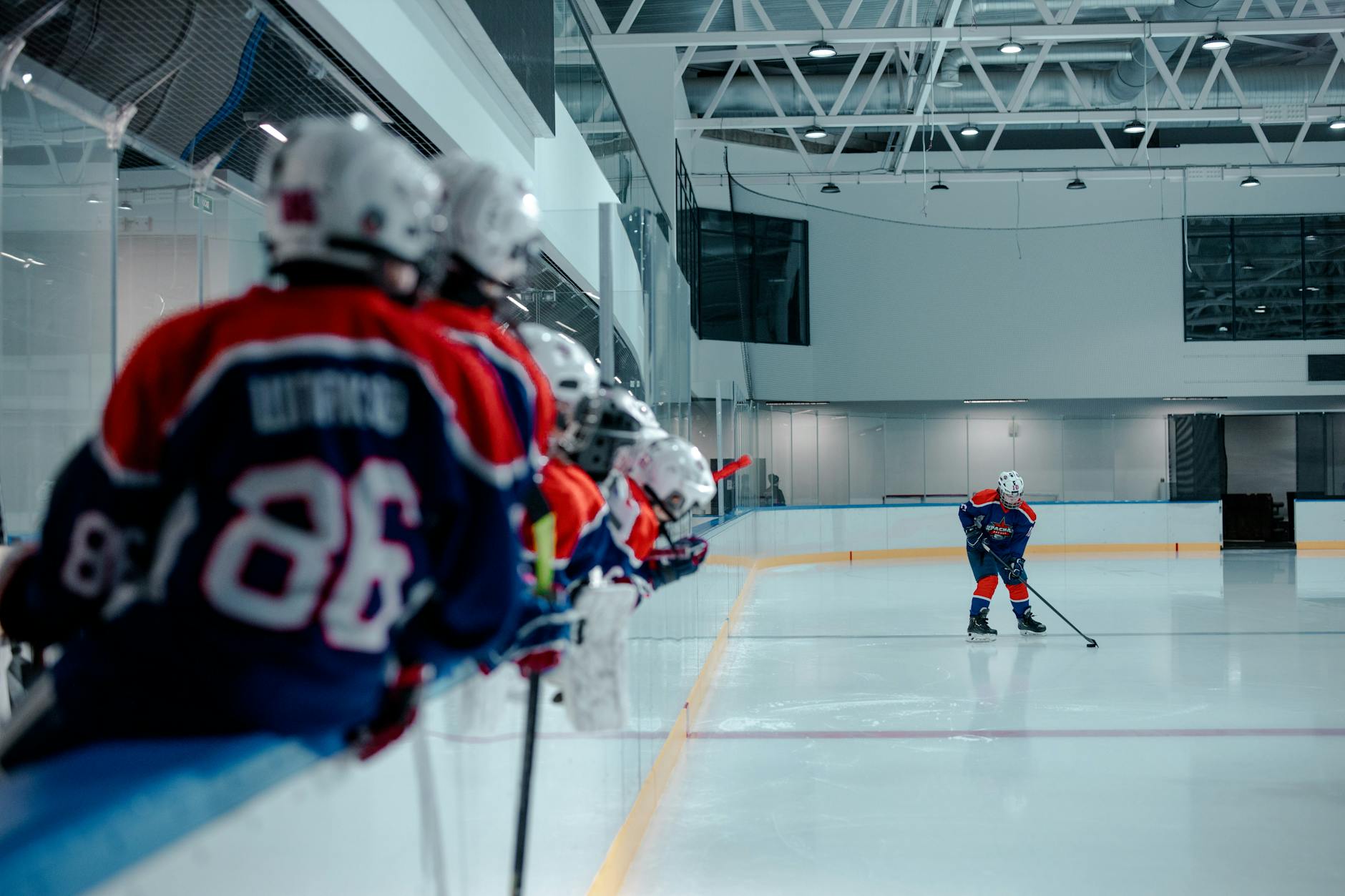 Ice hockey players on the rink, with a team in the foreground and an active player practicing.