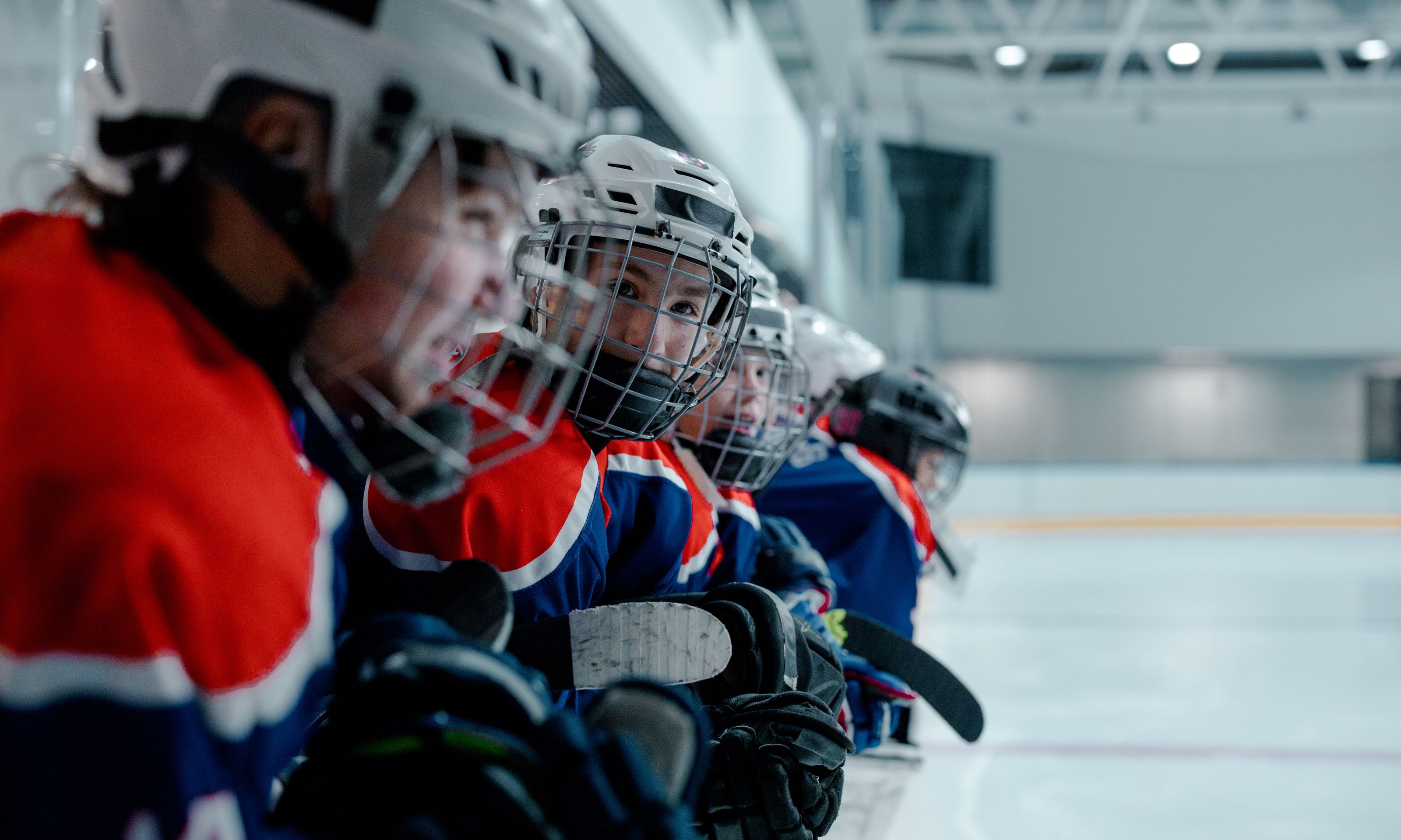 Youth ice hockey team in vibrant uniforms preparing for a game at an indoor ice rink.